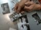 Close-up of handcuffed person examining crime scene photos on table, indicating investigation process.