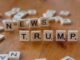 Wooden letter tiles spell 'NEWS' and 'TRUMP' on a wooden table, relating to political discourse.