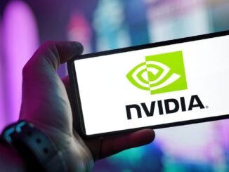 Close-up of a hand holding a smartphone showing the NVIDIA logo on screen with a blurred background.