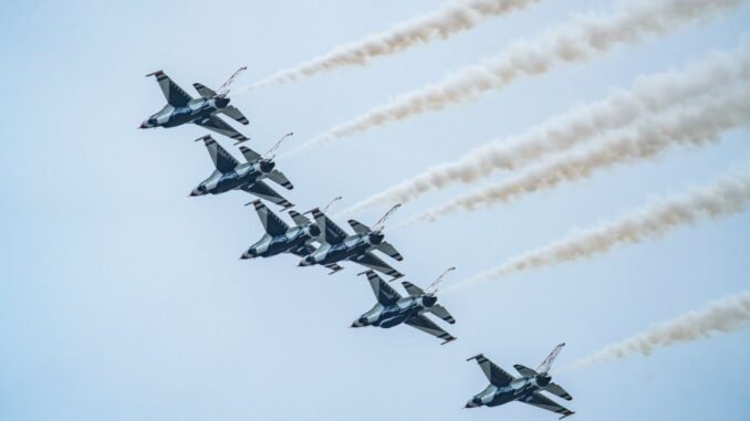 Aerial view of US Air Force Thunderbirds flying in formation against a blue sky.